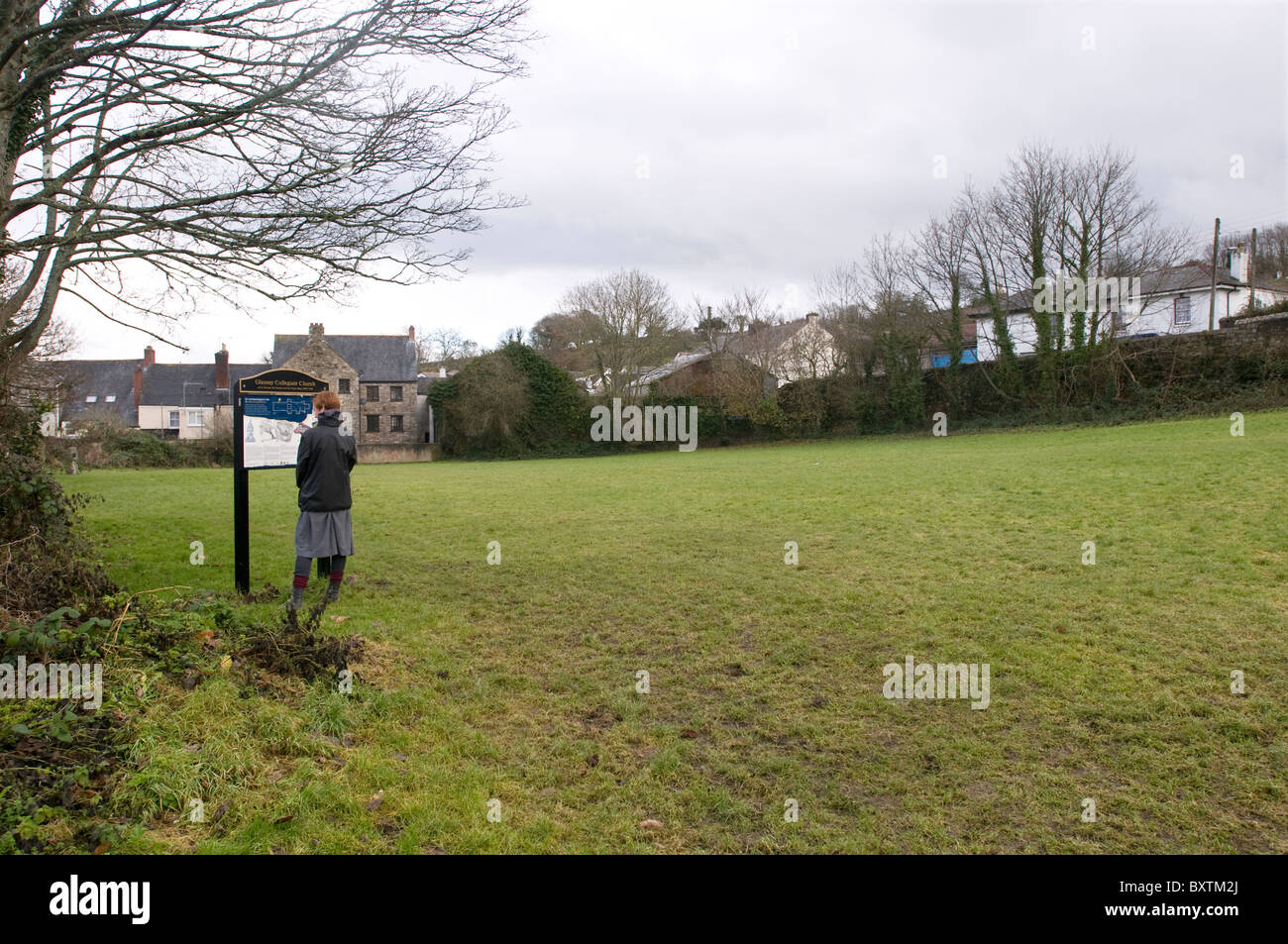 A  woman reads an information board on the site of Glasney College founded in 1265 in Penryn, Cornwall Stock Photo