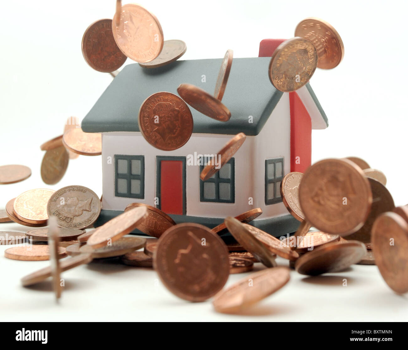 HOUSE WITH COINS DROPPING OVER IT RE PROPERTY MARKETS HOUSING COST BILLS  PRICES MORTGAGES FIRST TIME BUYERS ETC UK Stock Photo