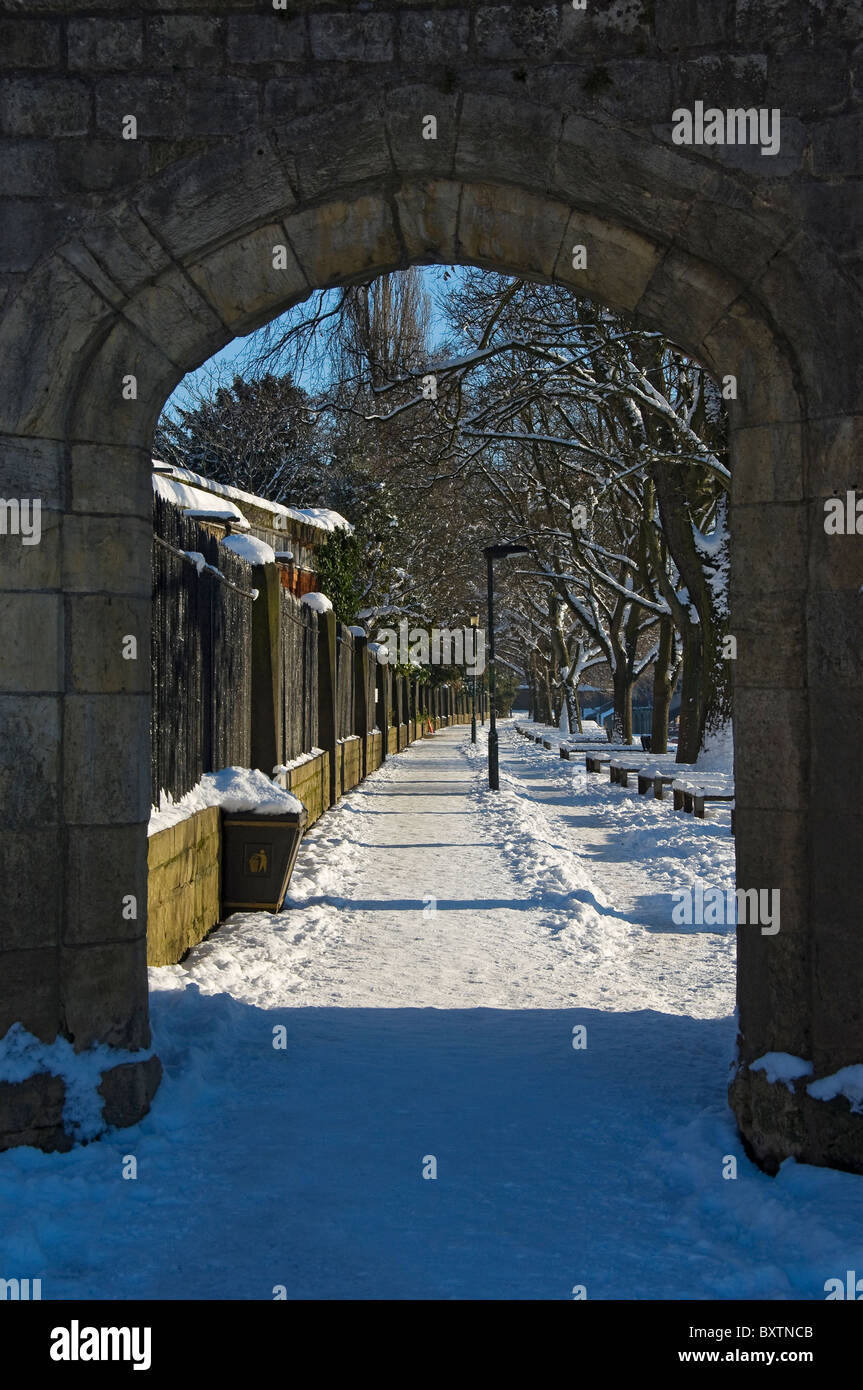 Looking through arch along footpath path snow covered in winter York North Yorkshire England UK United Kingdom GB Great Britain Stock Photo