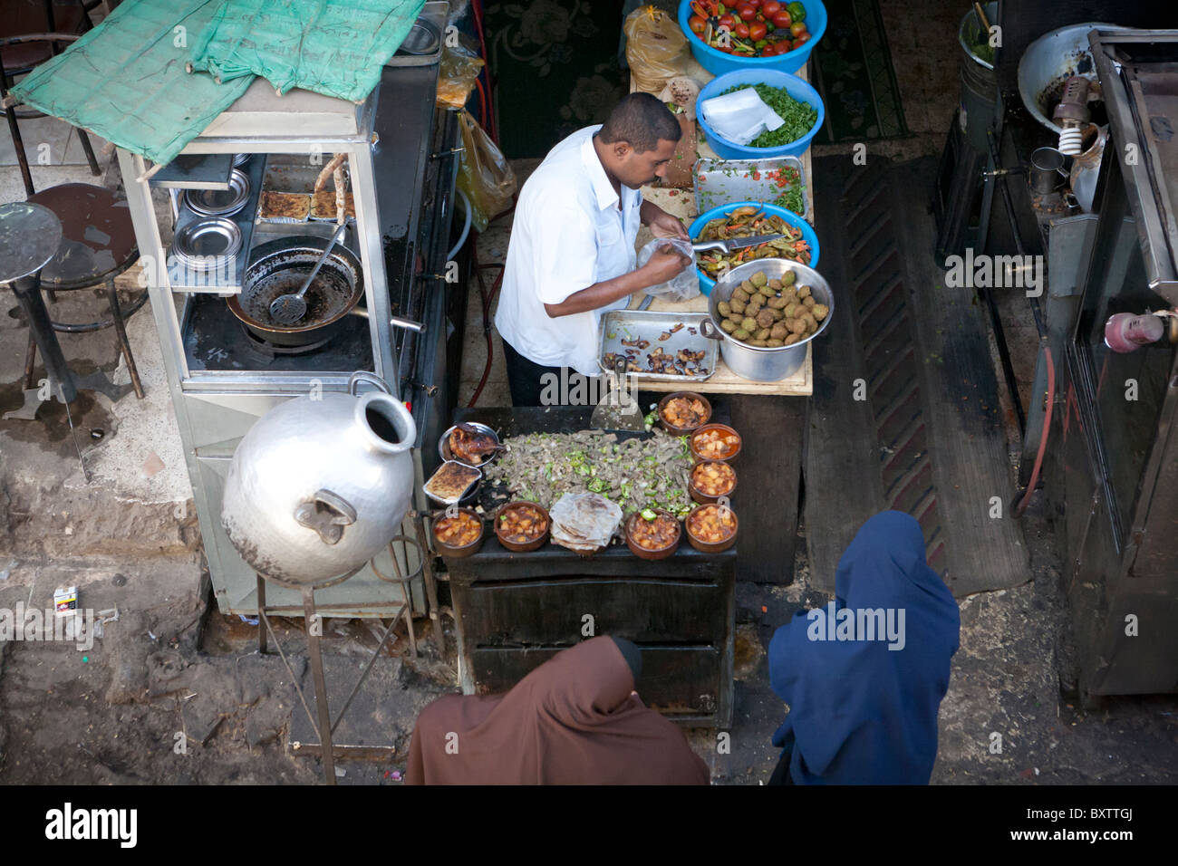 Local street market trader preparing food to serve two women at a street cafe in Luxor, Egypt, Africa Stock Photo