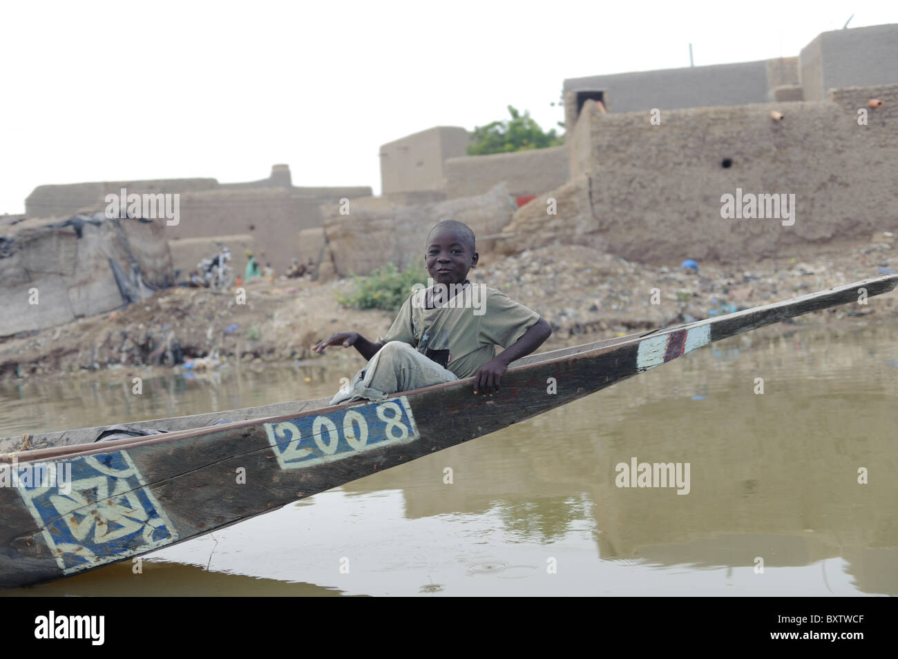 Young boy sitting on the bow of a pirogue. Djenné, Mali Stock Photo