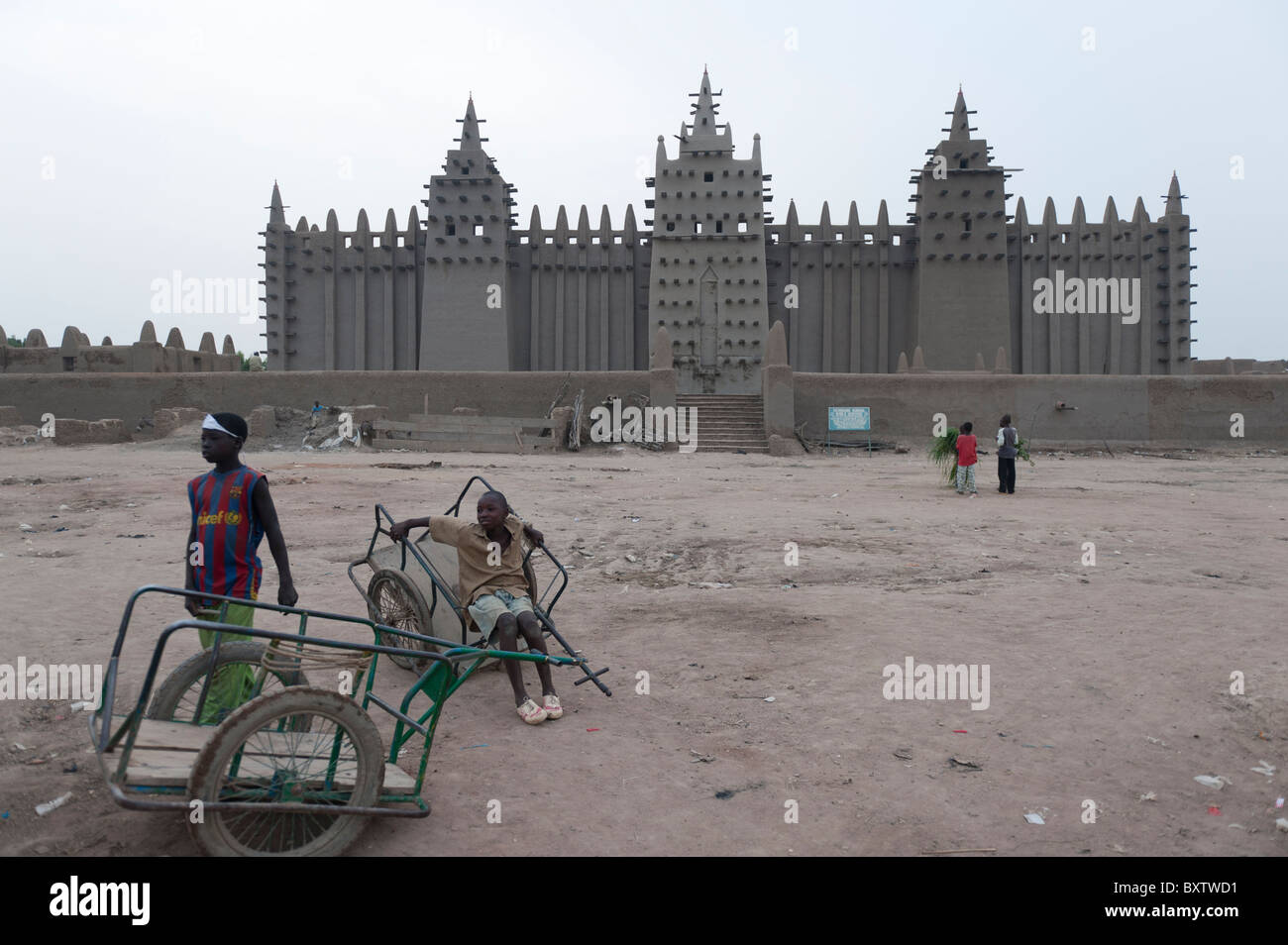 Boys with handcarts in front of the Great  Mosque of Djenné, Mali Stock Photo