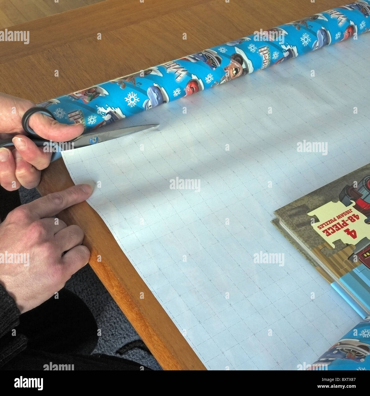 Caucasian Adult Male using scissors to cut wrapping paper, UK MODEL