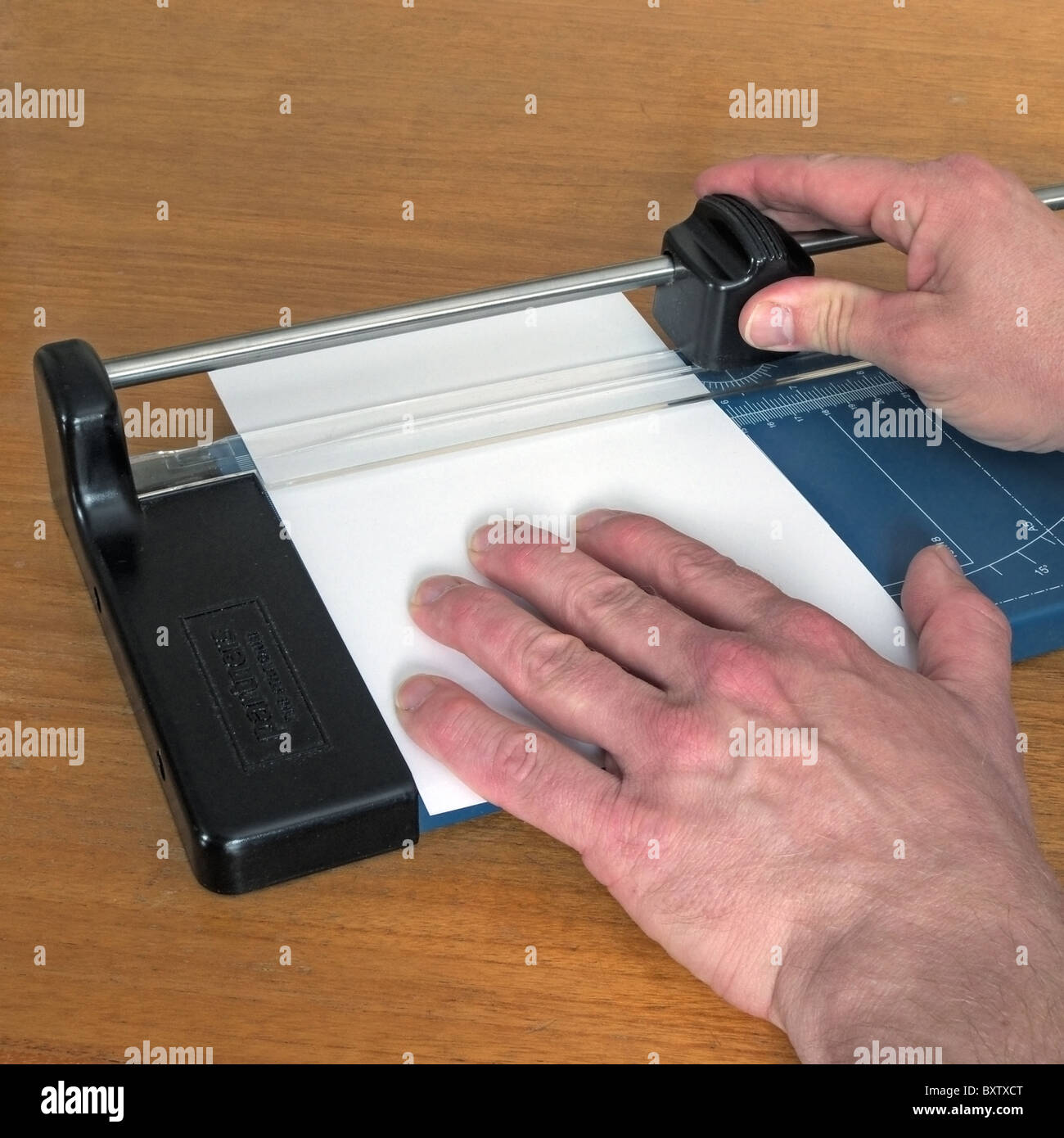 Caucasian Adult Male using a A4 Paper and Card Cutting Machine to cut
