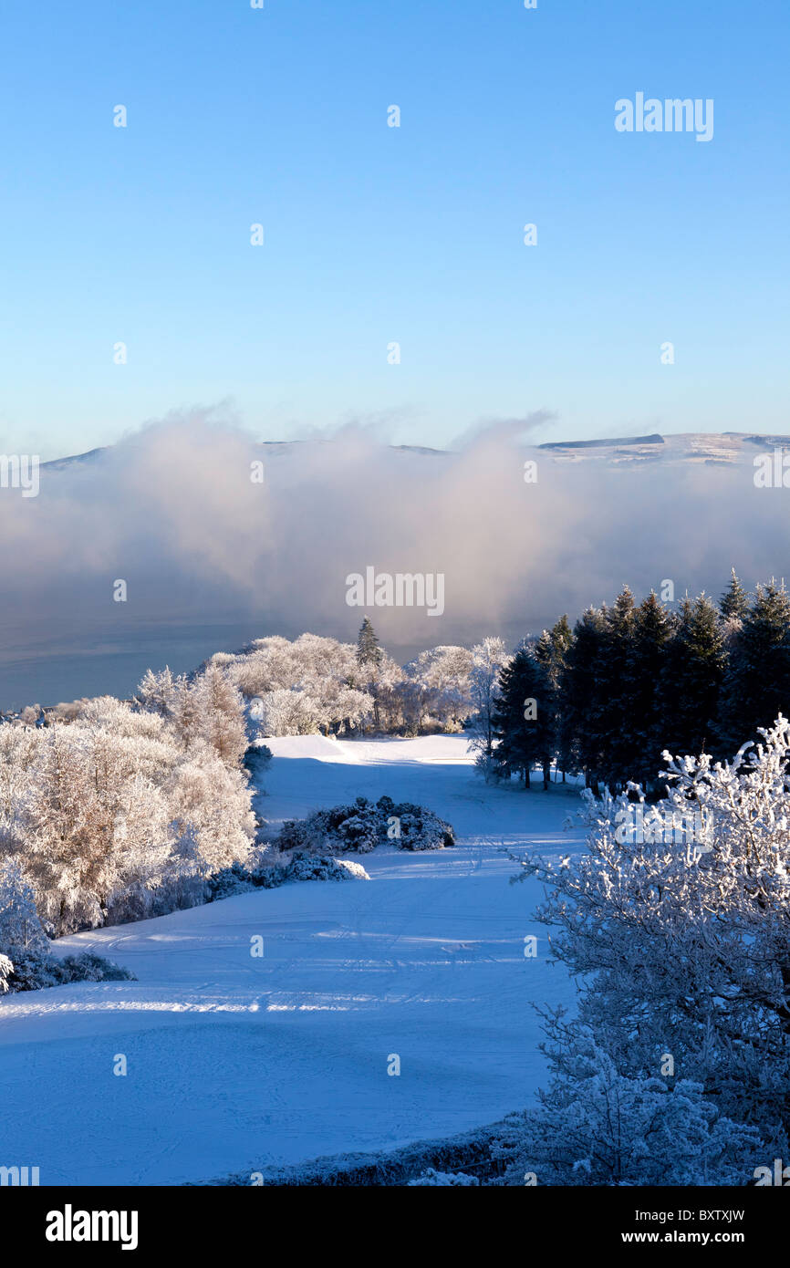 Lovely view over Greenock Golf course with snow covered fairway and mist on the river clyde Stock Photo