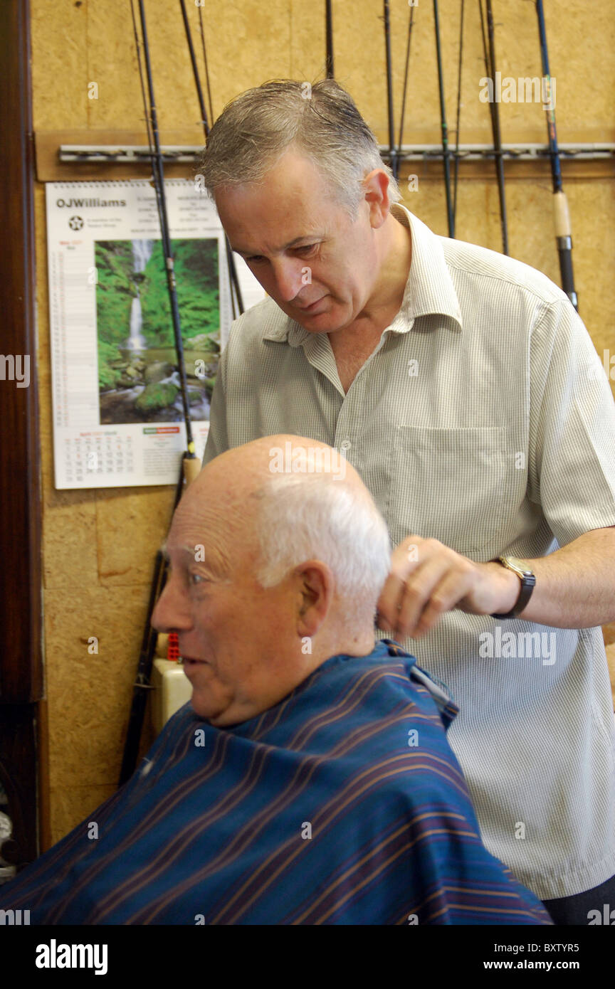 a old man has his hair cut in the barbers wish also sells