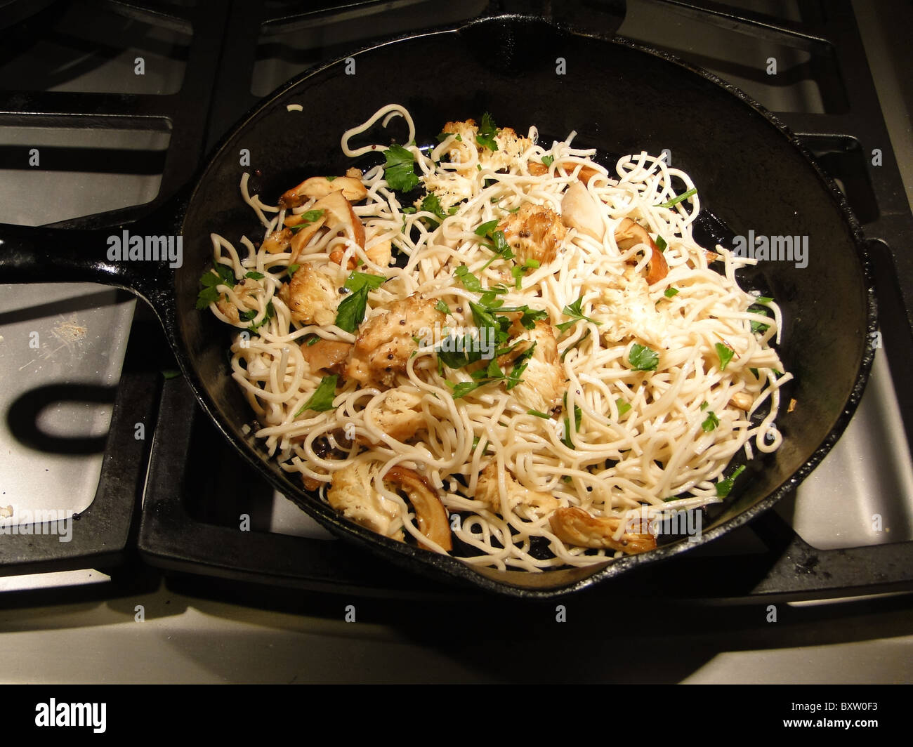 ramen noodles asian parsley wild mushroom fry saute stirfry cook castiron pan skilletfood fresh cooking raw Stock Photo