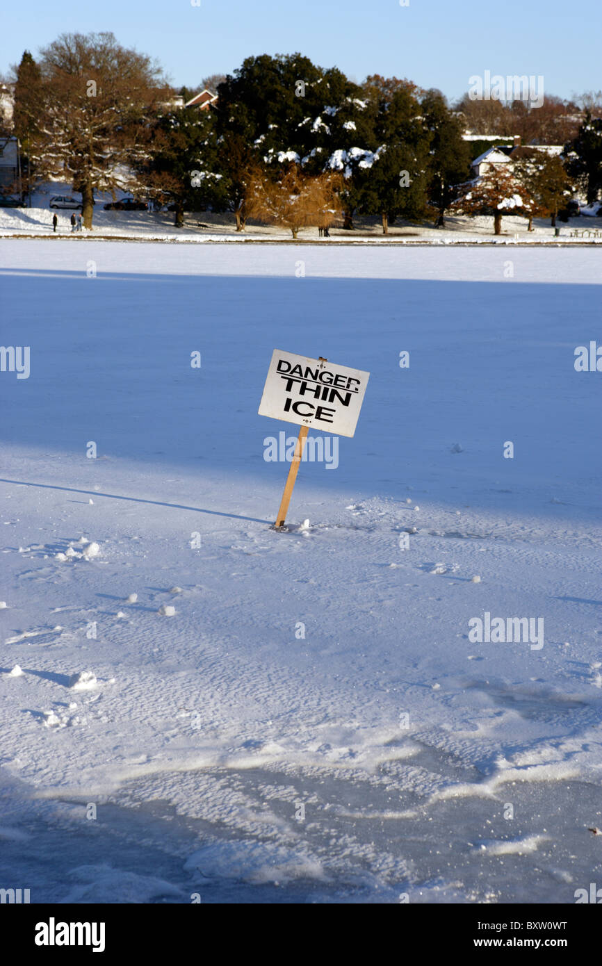 'Danger Thin ice' sign stuck in the ice on a lake Stock Photo