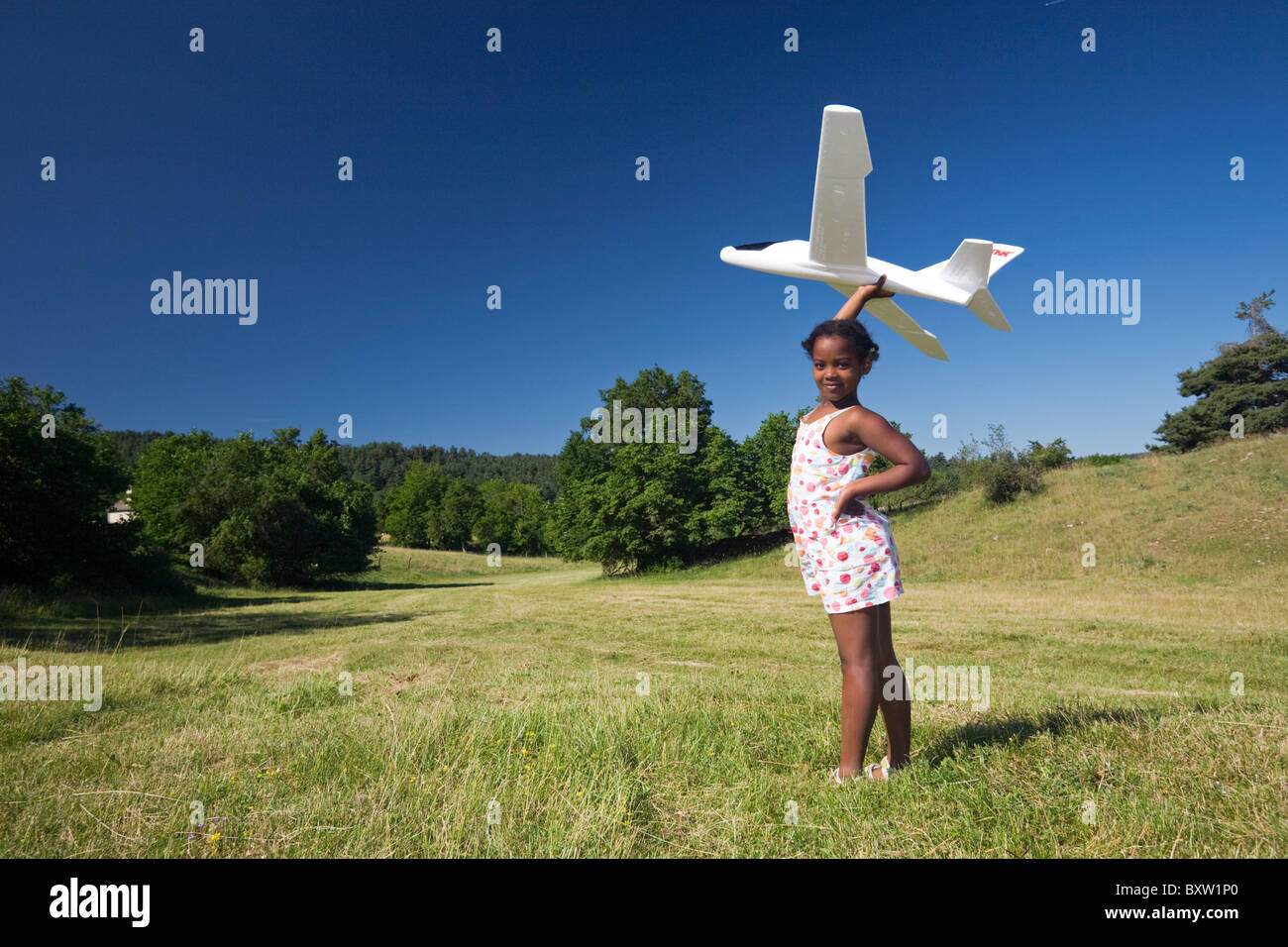 A little black girl playing with a scale model of a plane (France). Petite fille jouant avec un modèle réduit d'avion (France). Stock Photo