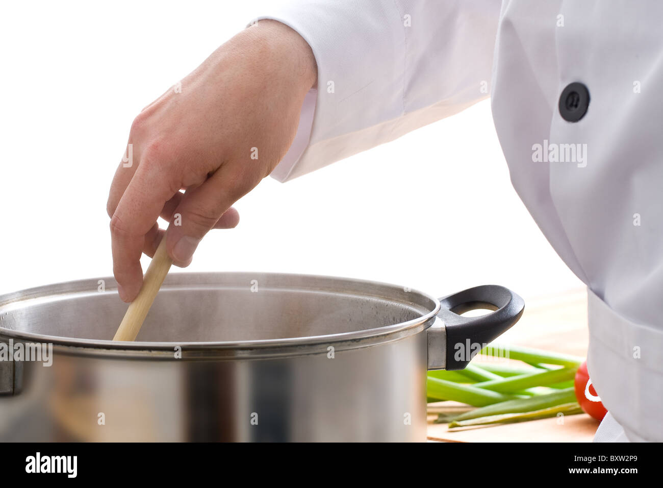 Chef stirring meal in pot on stove Stock Photo. 