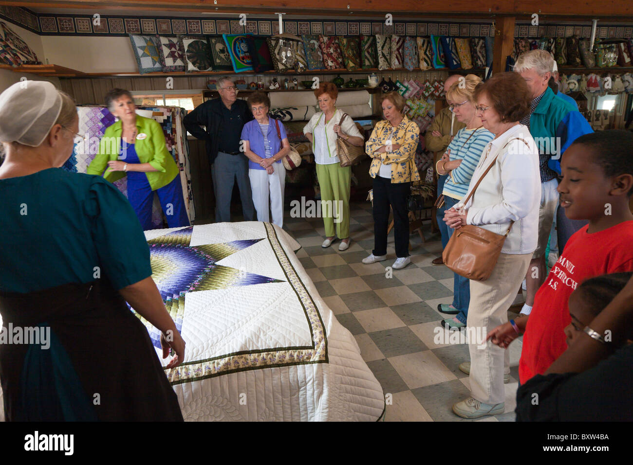 Amish woman shows quilts to tourists and shoppers in Lancaster County, Pennsylvania Stock Photo