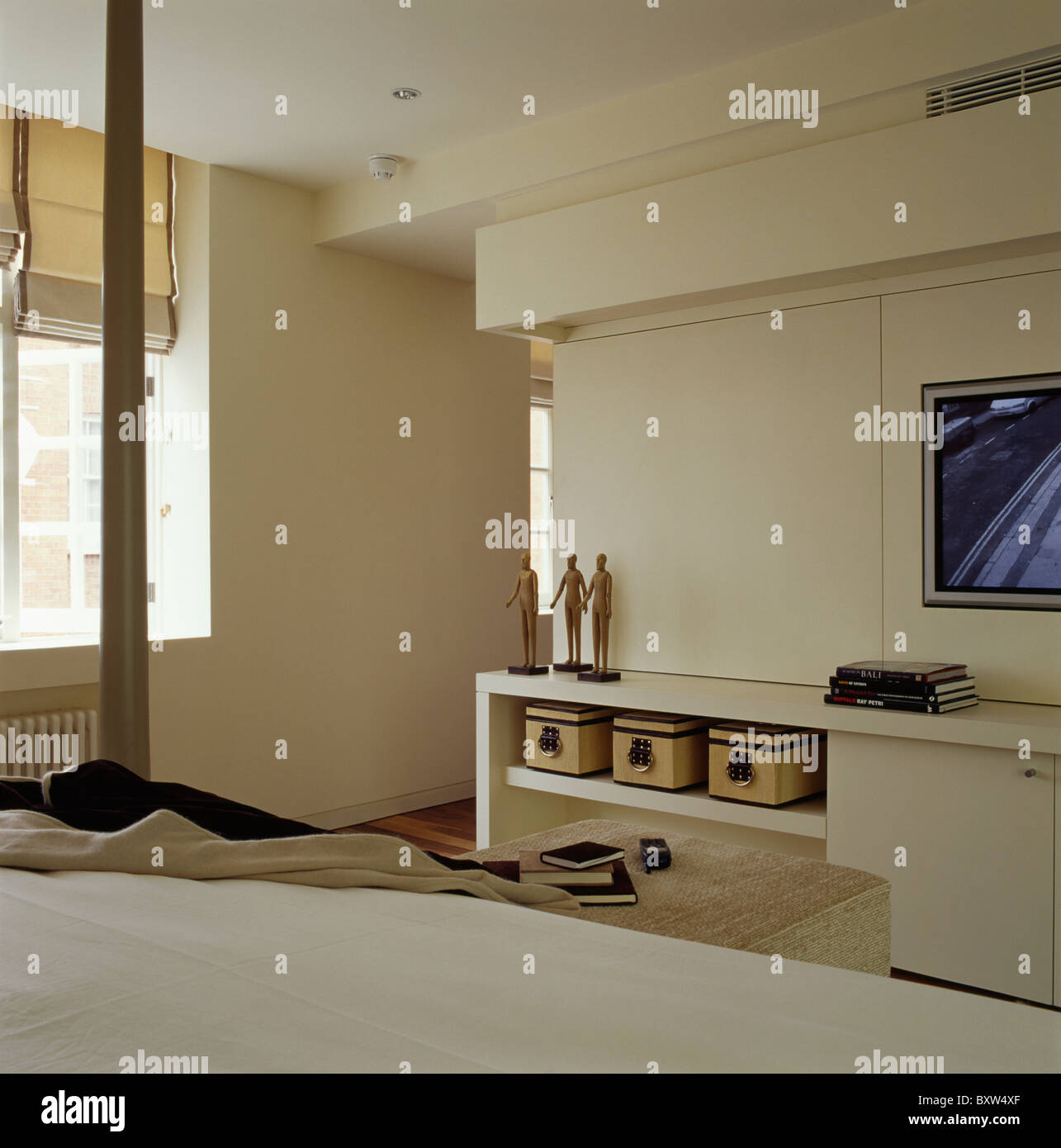 Modern cream townhouse bedroom with storage boxes on shelf of fitted cream unit Stock Photo
