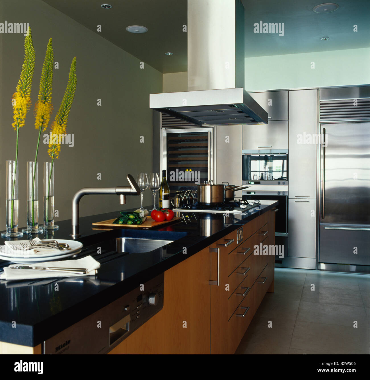 Tall yellow flowers in single glass vases above granite worktop with