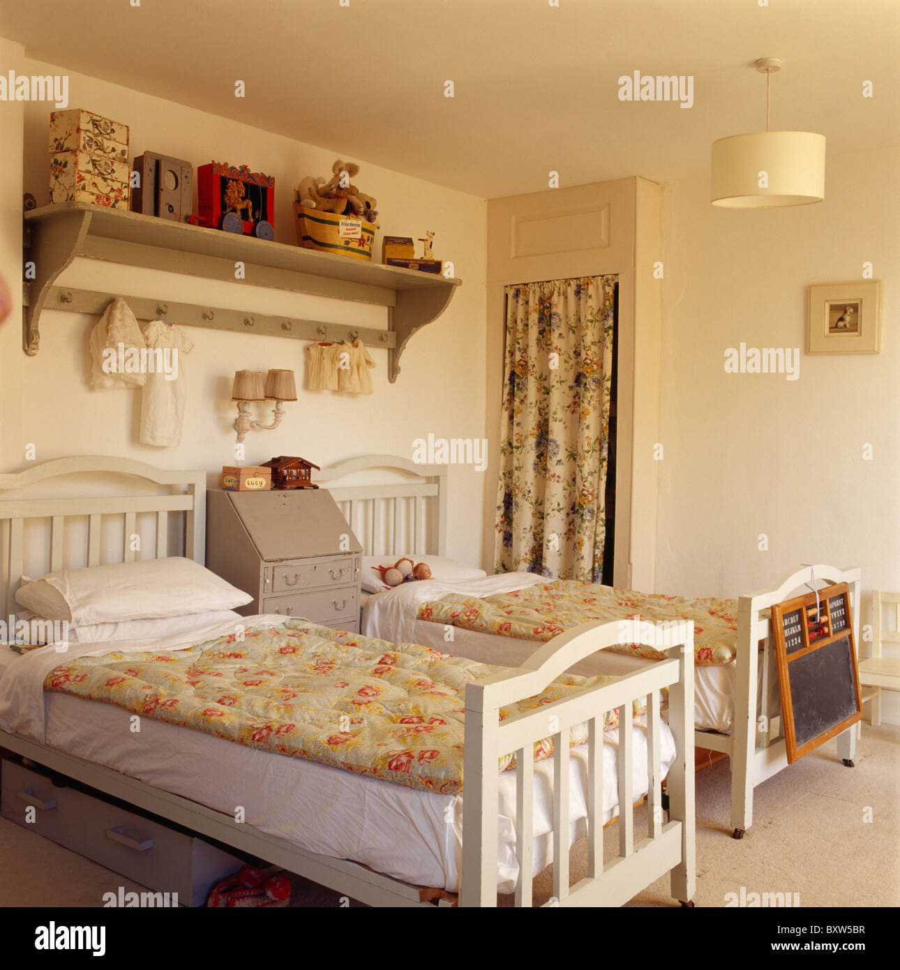 Floral quilts on cream twin beds in children's cream bedroom with shelf