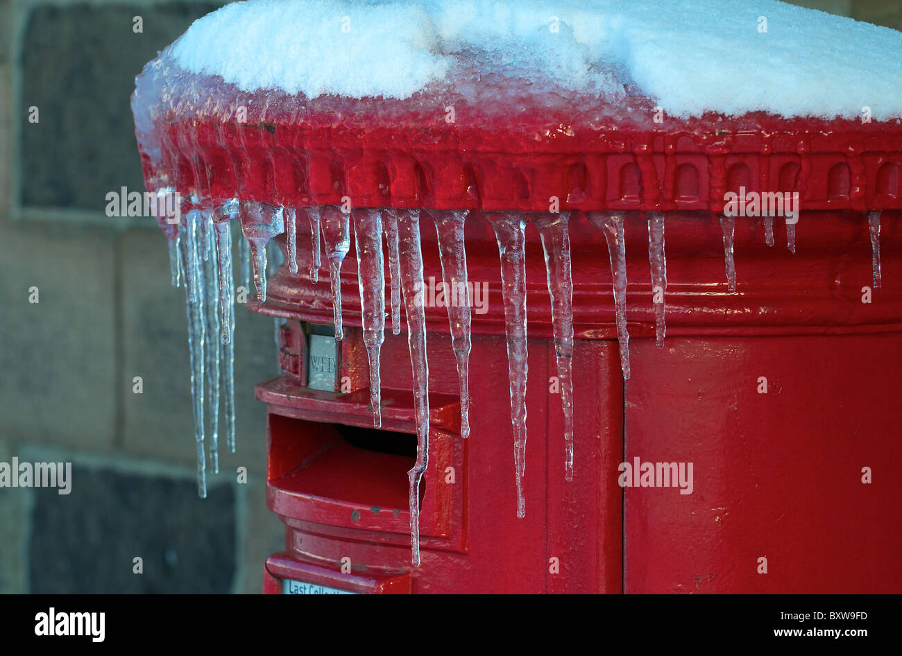 Icicles hanging from red post box Stock Photo