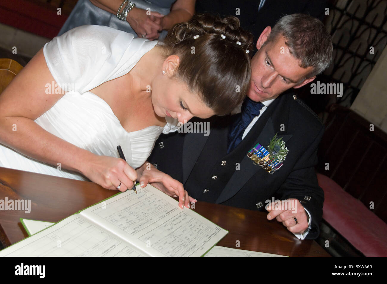 Horizontal close up portrait of a bride and groom signing the official register following their traditional church wedding. Stock Photo