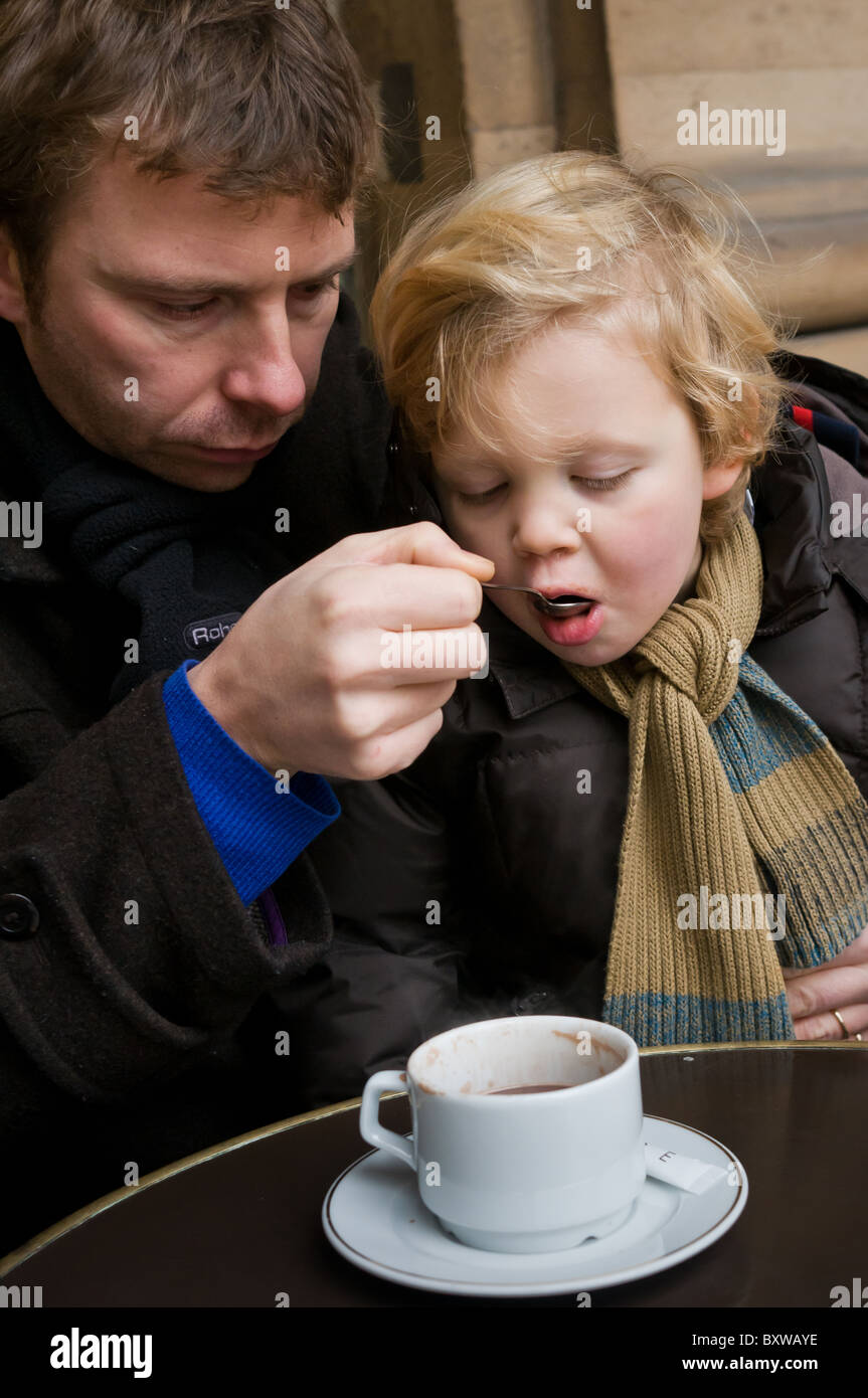 Father and his son enjoy some hot chocolate at an outside Paris café in ...