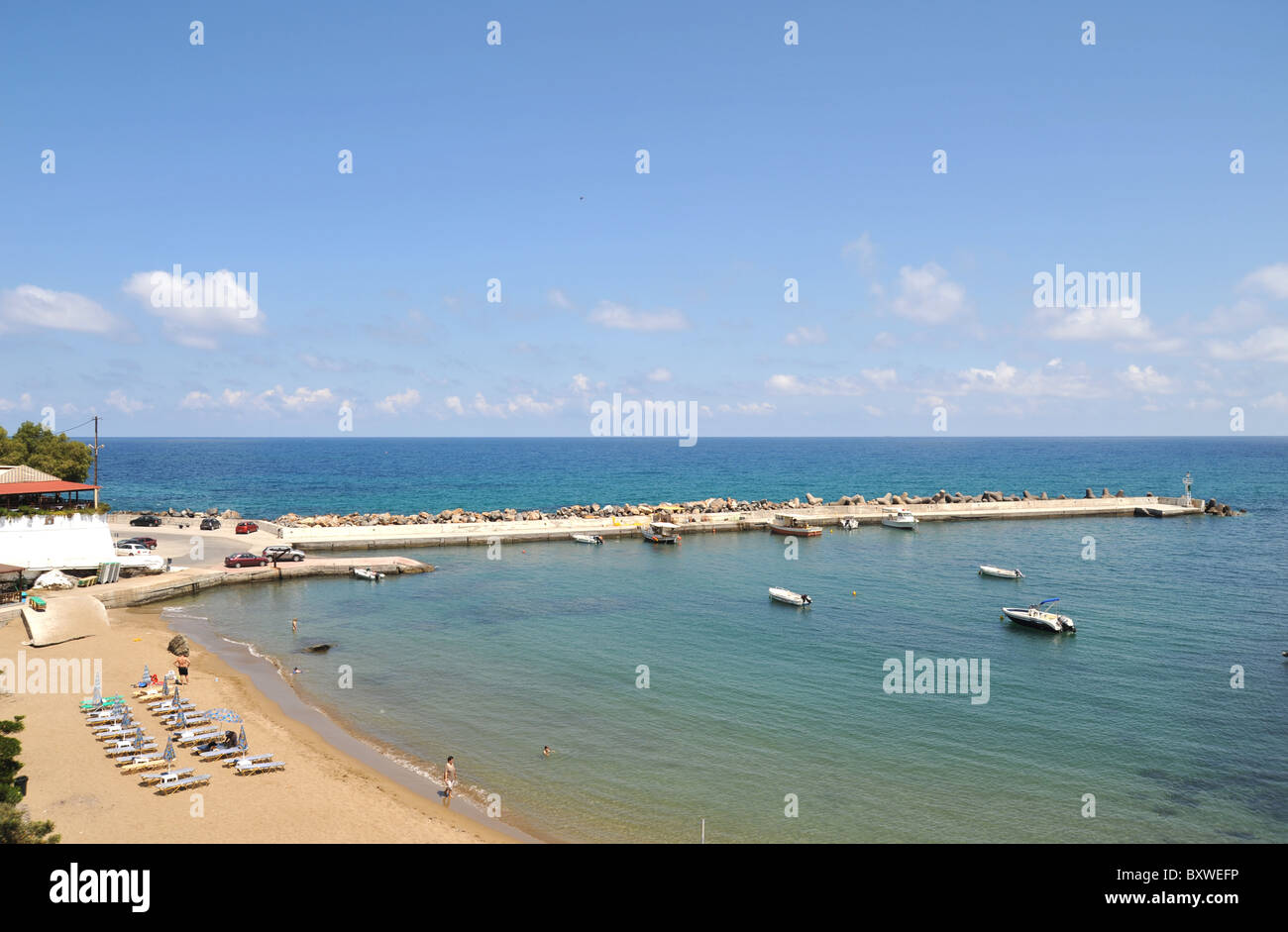 The wide sandy beach and harbour wall at Panormo, Crete, Greece Stock Photo