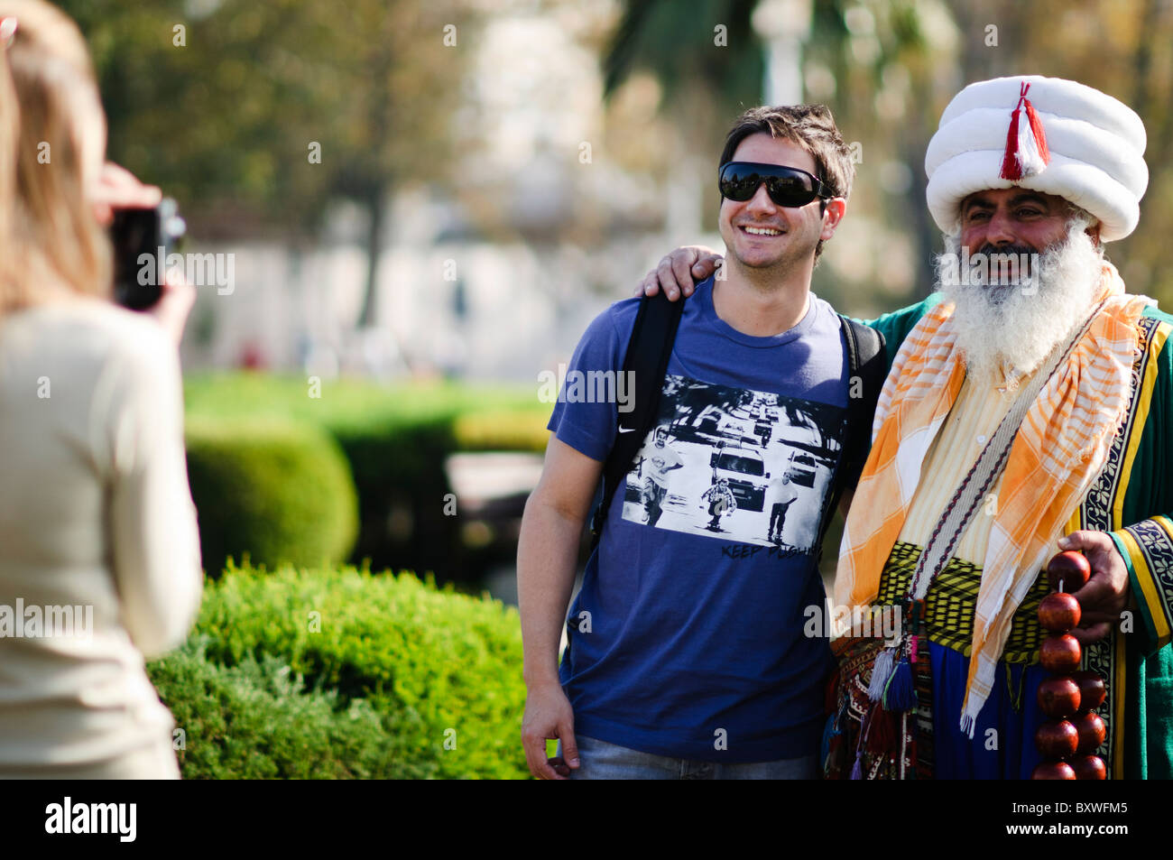 ISTANBUL, Turkey / Türkiye — Tourists pose for a photo with a street performer dressed in the costume of an Ottoman sultan near the Blue Mosque in Istanbul, Turkey. Stock Photo