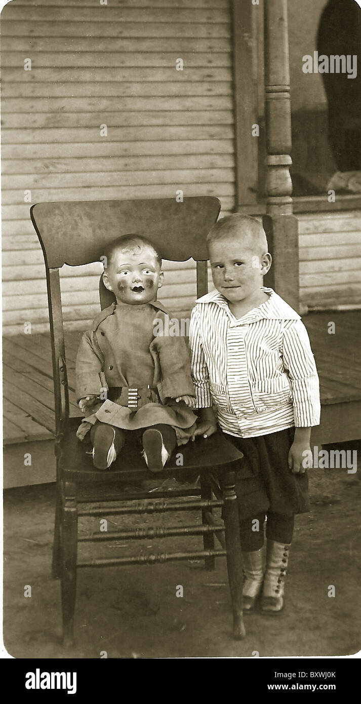 A boy and his doll on the porch; High-button shoes, c. 1910-1915 Stock Photo