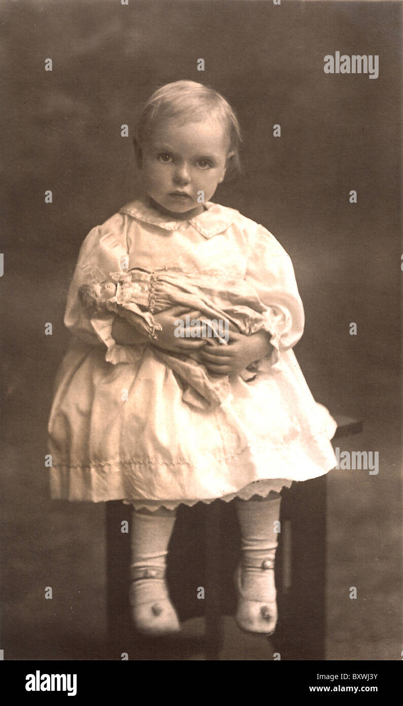 'The Doll'.  Antique photo of child holding doll. c. 1910-1915 Stock Photo