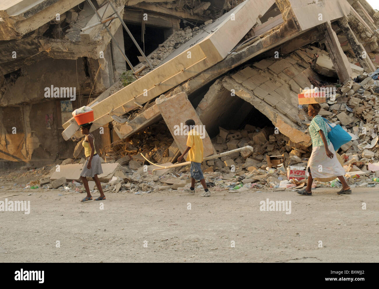 People walk past building collapsed by the Haiti earthquake of 2010 Stock Photo