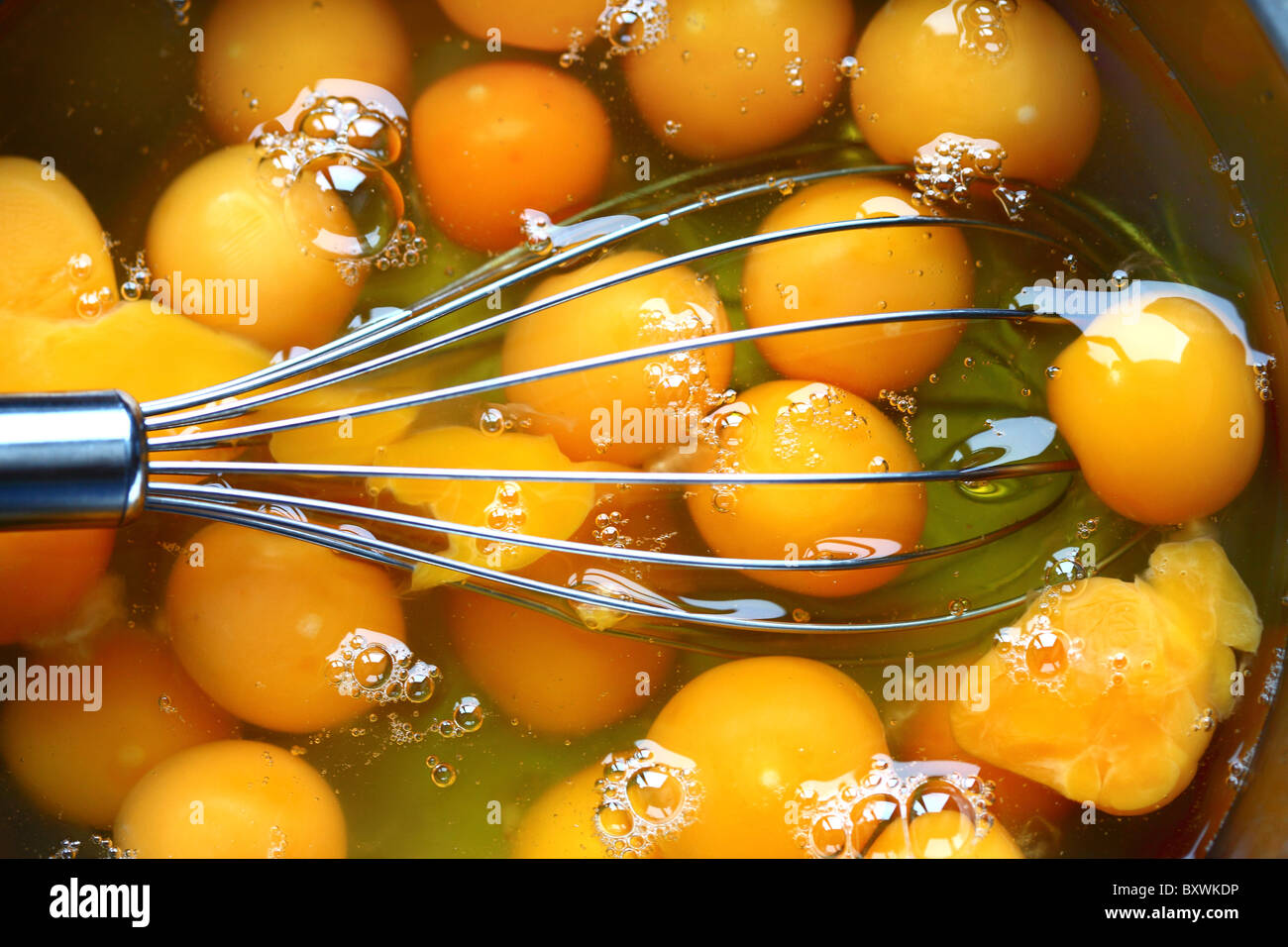 Raw eggs in a bowl, egg white and egg yolk, eggbeater, ready to whisk. Stock Photo