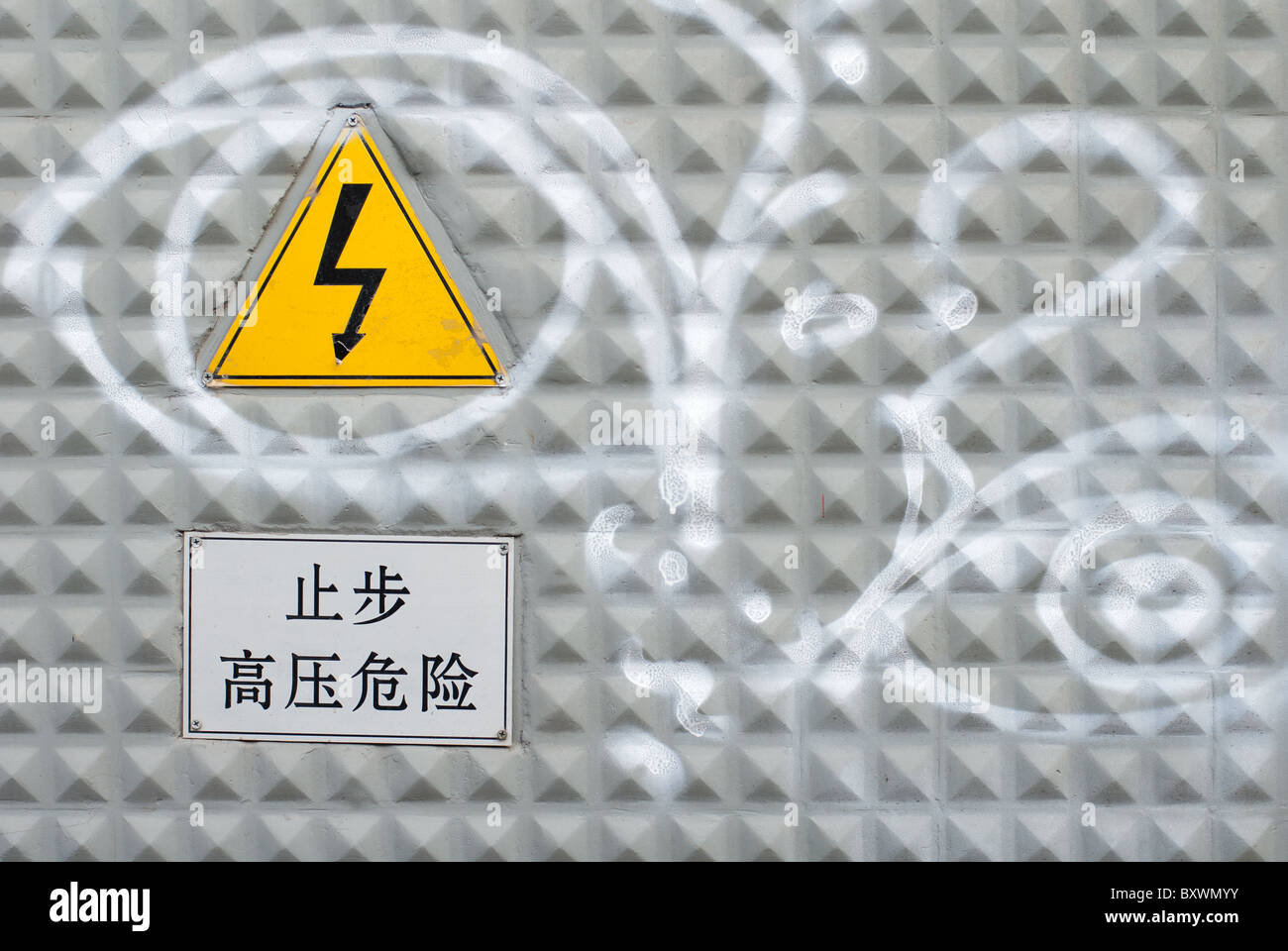 simple graffiti on a high-voltage control cabinet's door, with danger signs Stock Photo