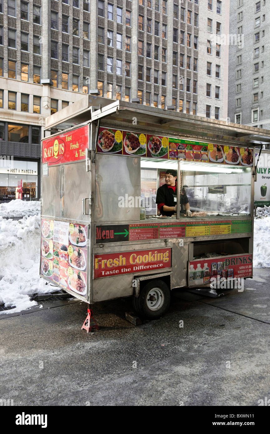 genial cook works inside food cart on Park Avenue south Manhattan in winter setting after December 2010 blizzard Stock Photo