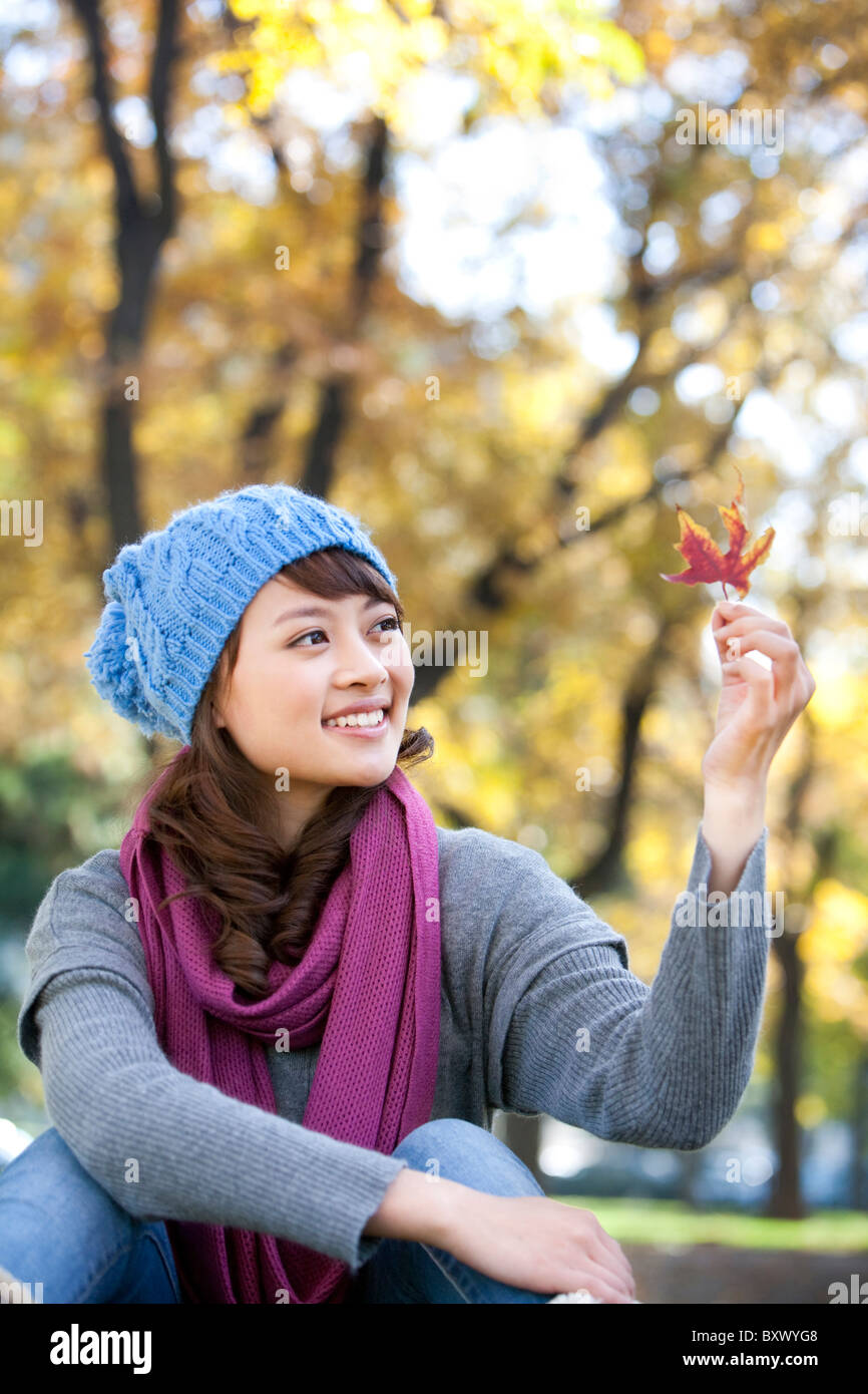 Young Woman Looking At Maple Leaf Stock Photo