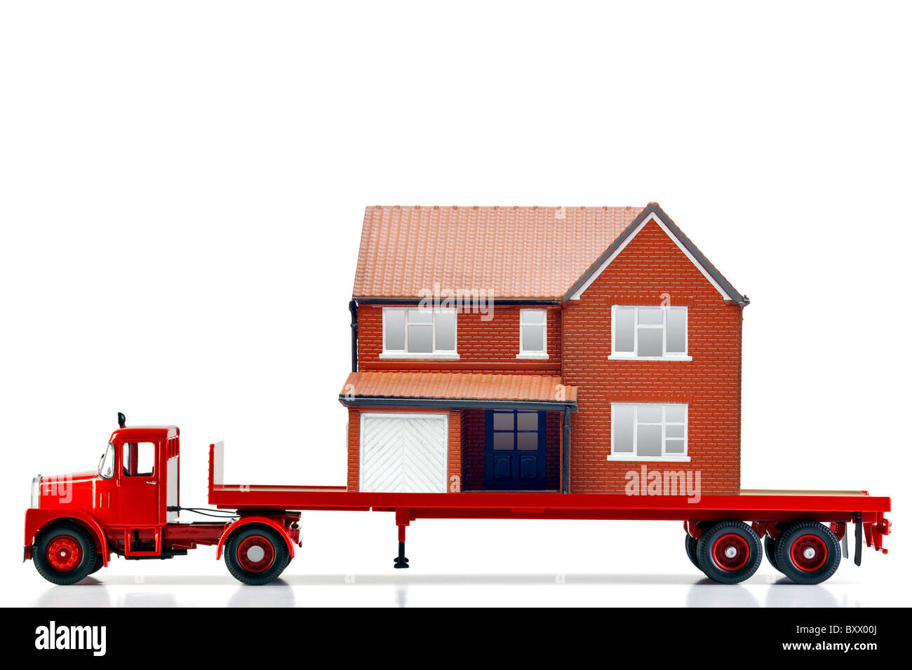 A flatbed articulated lorry loaded with a house isolated on a white background. Both are models. Stock Photo