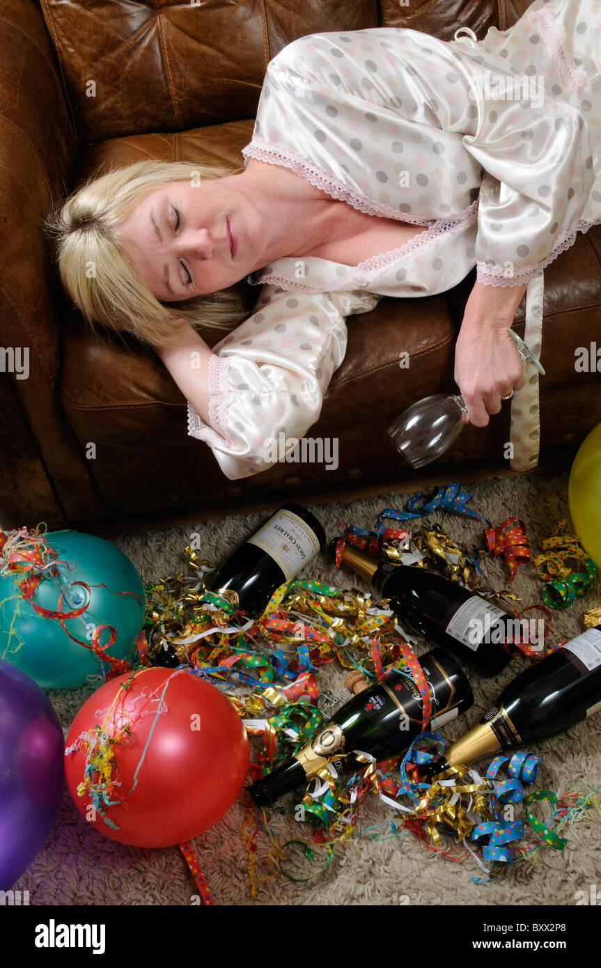 Woman holding an empty wine glass laying on a sofa and sleeping of a