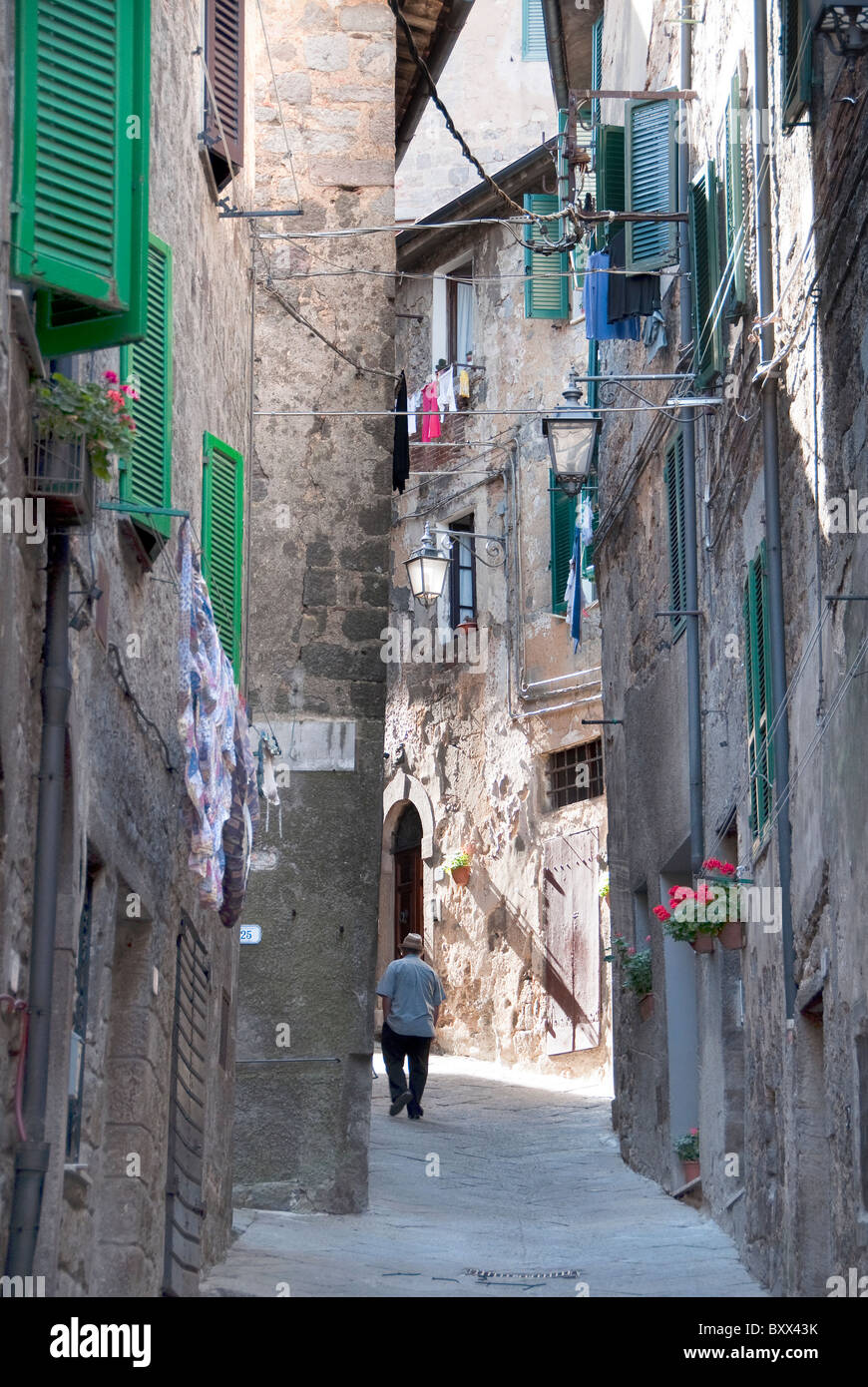 Back view of male tourist walking up the narrow streets of Piancastagnaio on the slopes of Mount Amiata, Tuscany Italy Stock Photo