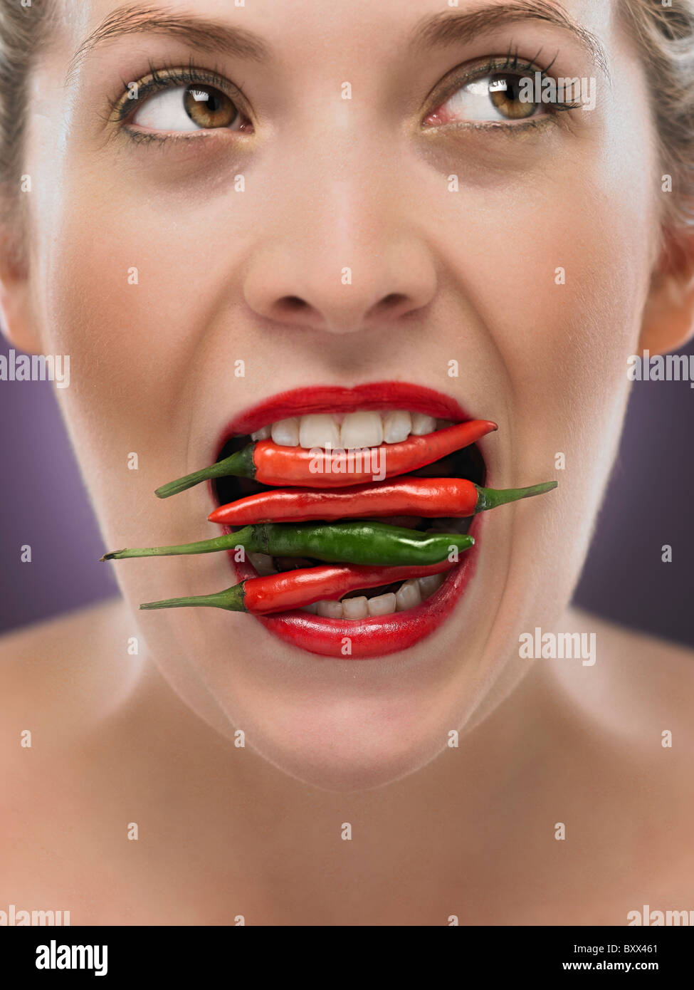 white blonde woman with chili's in her mouth Stock Photo