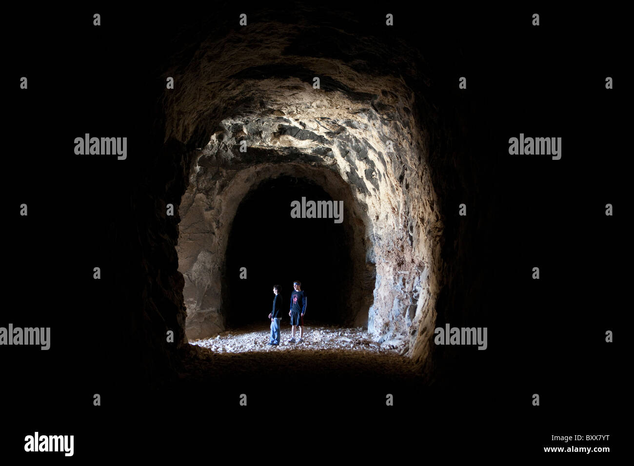 Hikers inside abandoned railroad tunnel in West Texas look across Rio Grande River into Mexican state of Coahuila Stock Photo