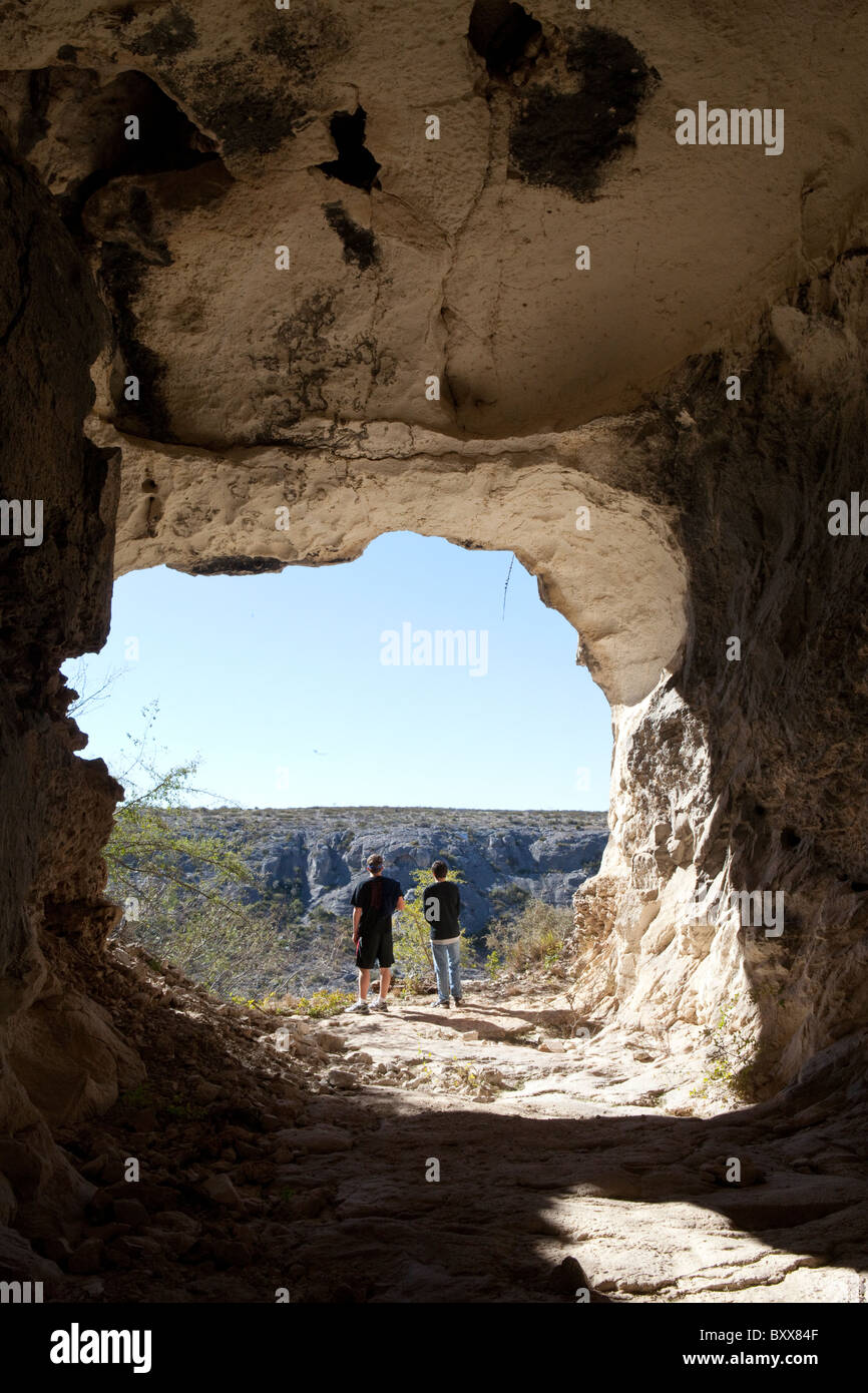 Hikers at entrance to abandoned railroad tunnel in West Texas look across Rio Grande River into Mexican state of Coahuila Stock Photo