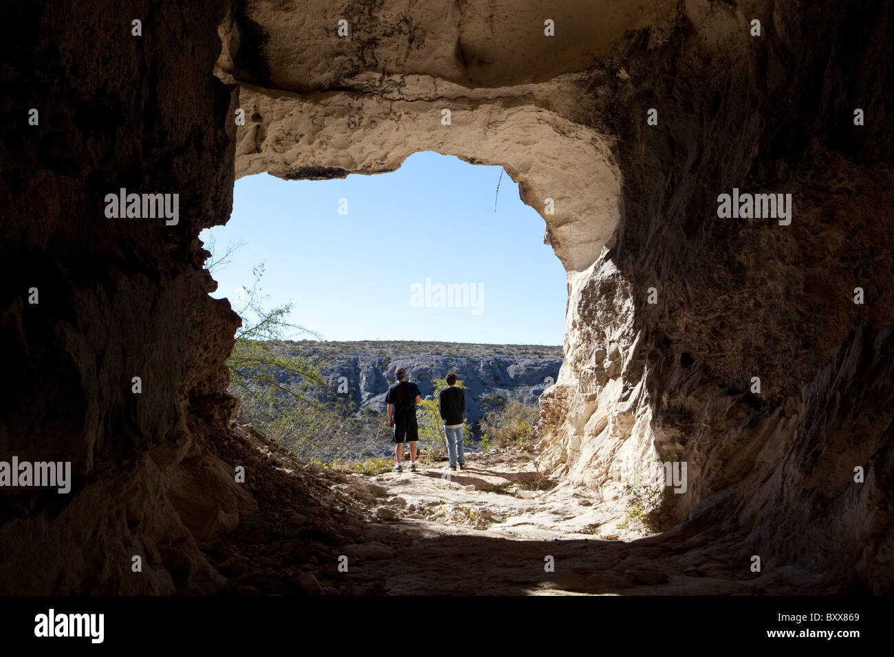 Hikers at entrance to abandoned railroad tunnel in West Texas look across Rio Grande River into Mexican state of Coahuila Stock Photo