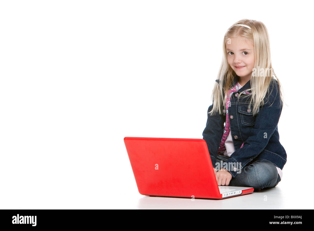 Cute little girl sitting down with laptop isolated on white background ...