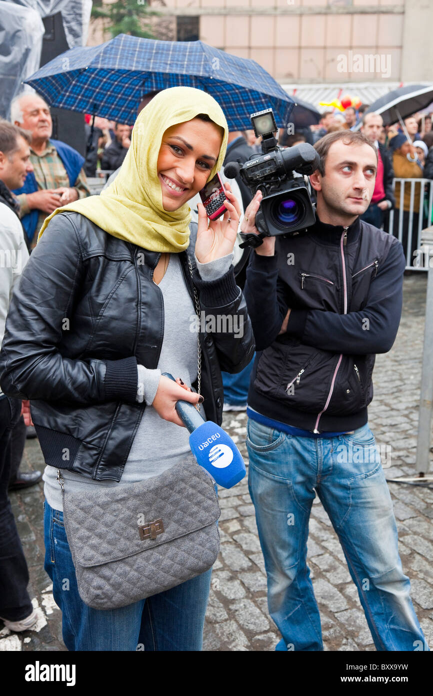 Young woman television news reporter on cellphone and cameraman in Tbilisi, Georgia. JMH4081 Stock Photo