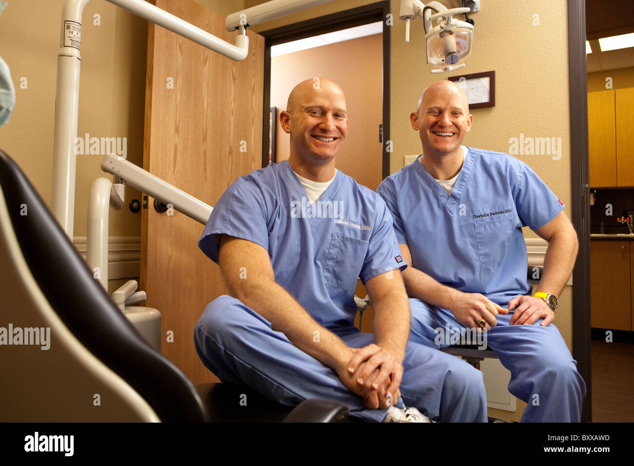Dentists who are identical twins pose in a treatment room in the clinic where they practice together in Austin, Texas USA. Stock Photo