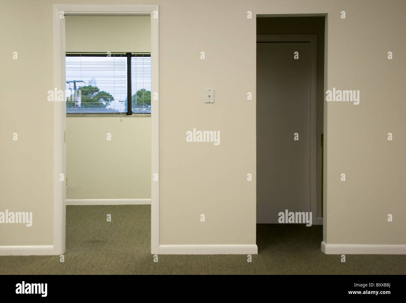 Two doorways in modern office space, one open door shows windows to the outside Stock Photo