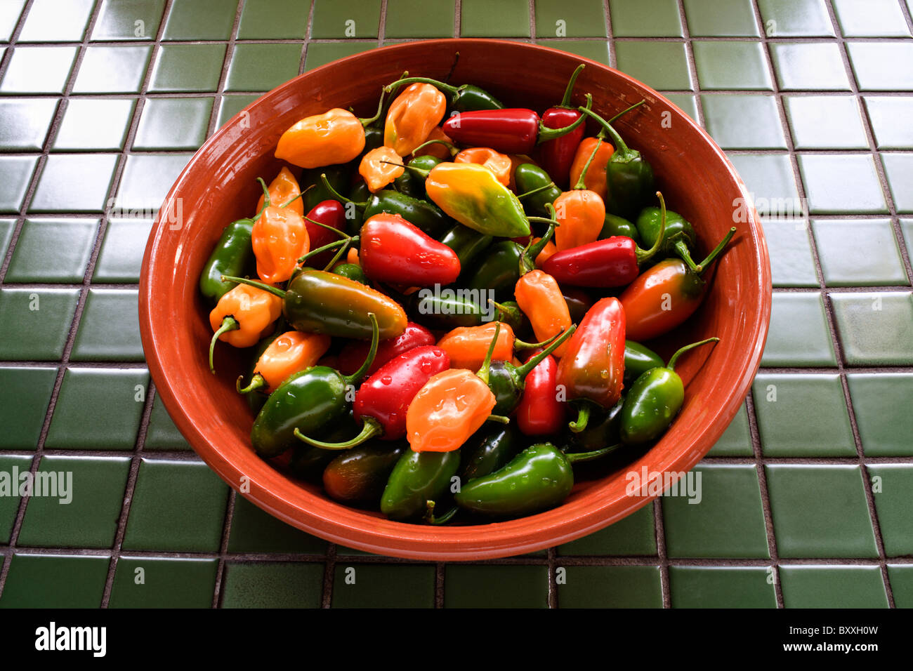 Bowl of Habanero and Jalapeno chili peppers on tile counter top Stock