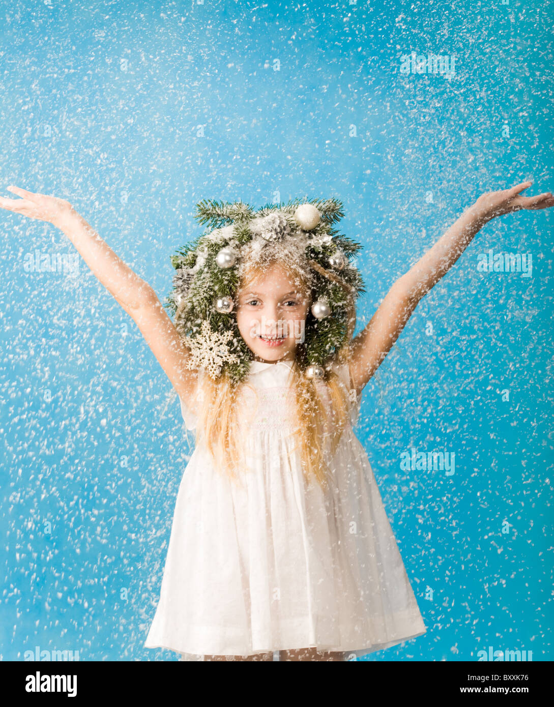 Portrait of joyful girl wearing white dress and wreath enjoying flurry ...