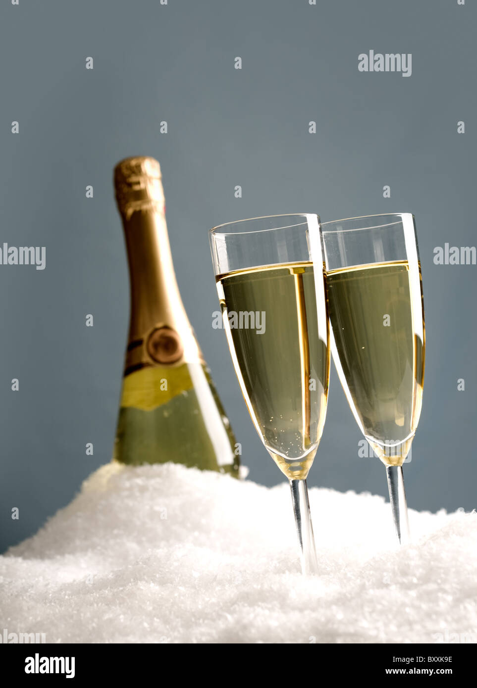 Vertical photo of two champagnes with bottle at background in snow Stock Photo