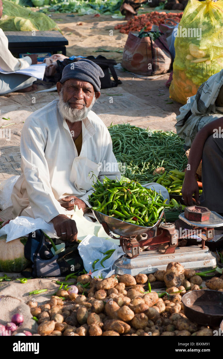Muslim man weighing green chillis at a vegetable market in Puttaparthi, Andhra Pradesh, India Stock Photo