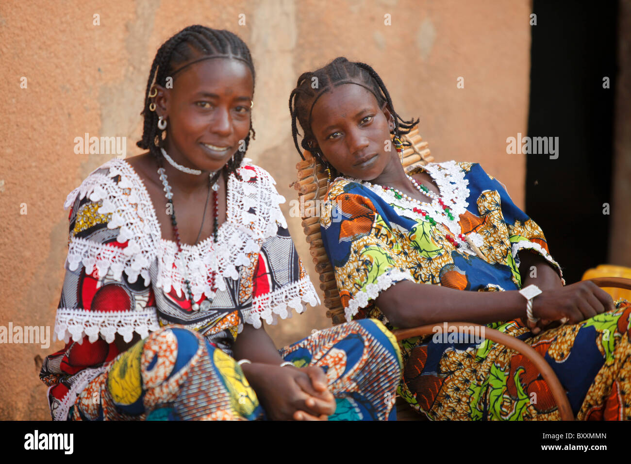 Two young Fulani women sit in front of a house in the town of Djibo in northern Burkina Faso. Stock Photo