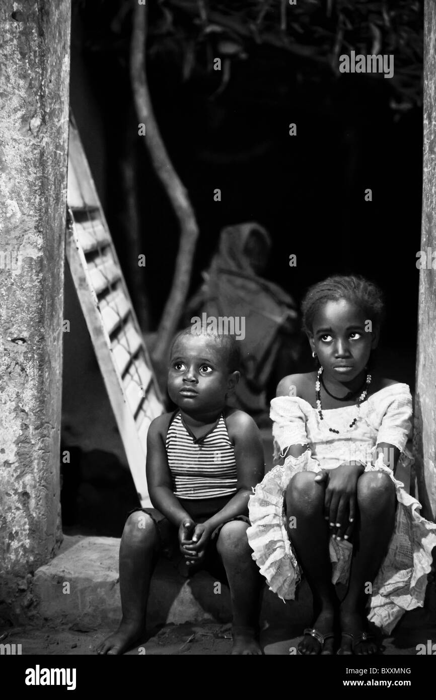 Two cousins sit in the doorframe of a house at night in Djibo in northern Burkina Faso. Stock Photo