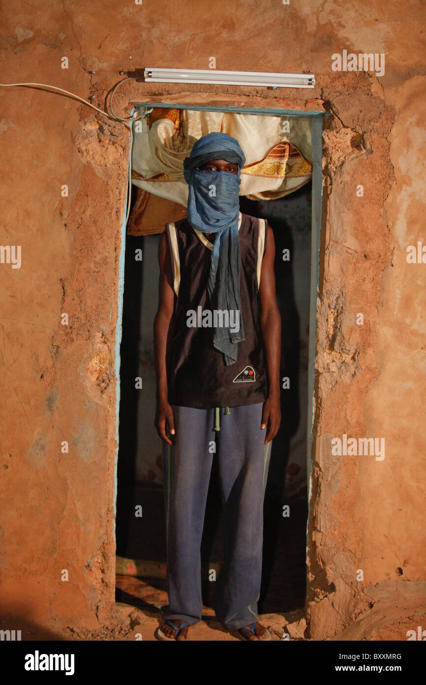 A young Fulani man in a turban stands in the doorframe of his home in Djibo, northern Burkina Faso. Stock Photo