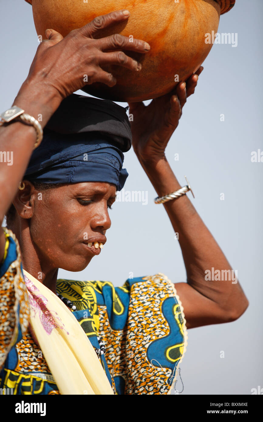 A Fulani woman arrives in the town of Djibo, Burkina Faso on foot, carrying fresh milk for sale in a calabash. Stock Photo