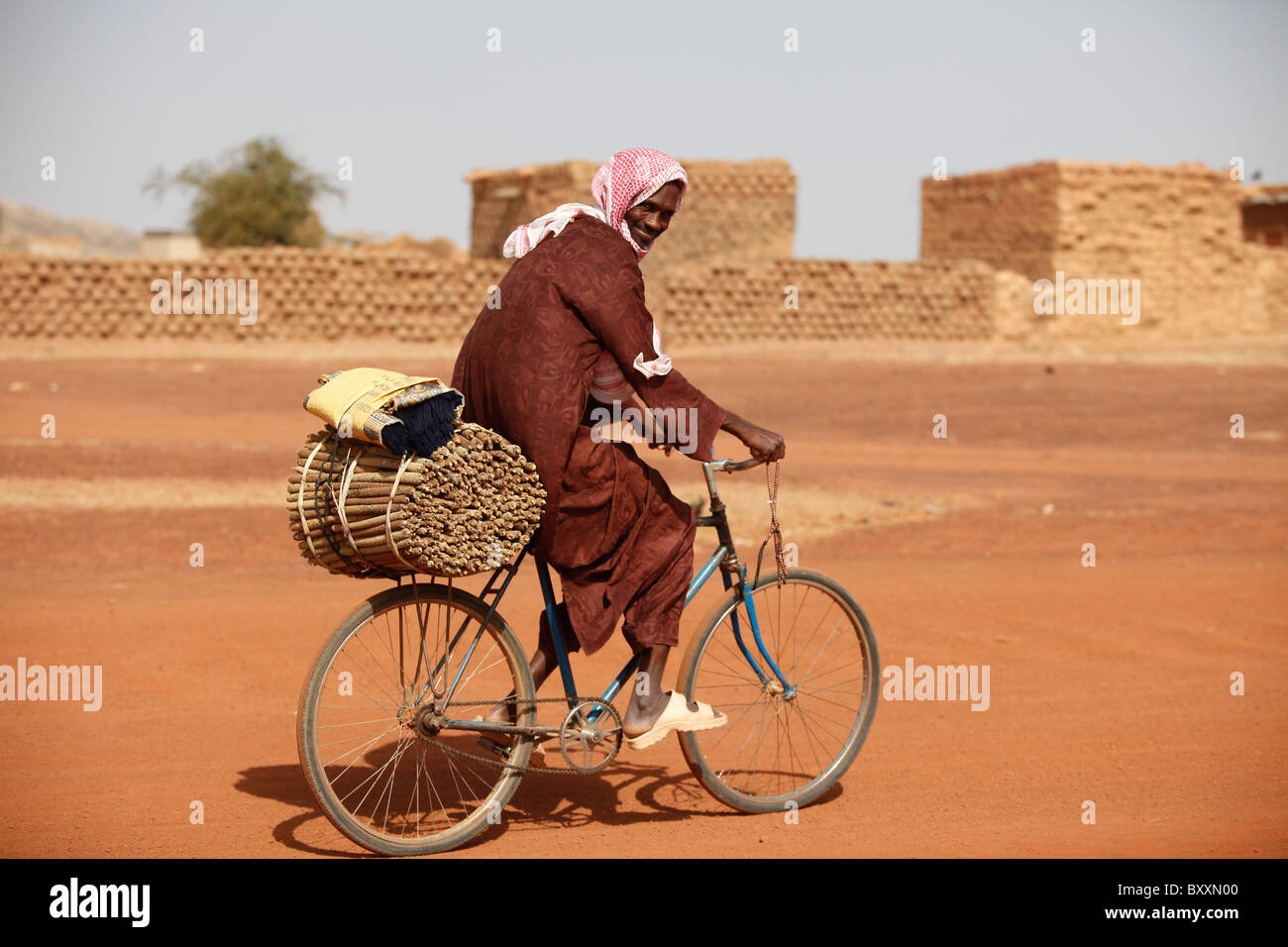 A man rides through the town of Djibo, Burkina Faso with harvested millet on his bicycle. Stock Photo